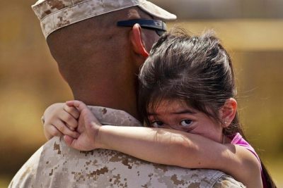 sad girl looking over the shoulder of her dad in uniform